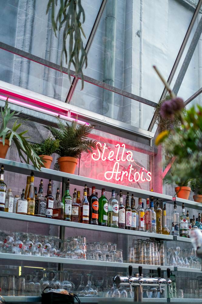 Neonlicht Stella Artois boven schap met sterke dranken